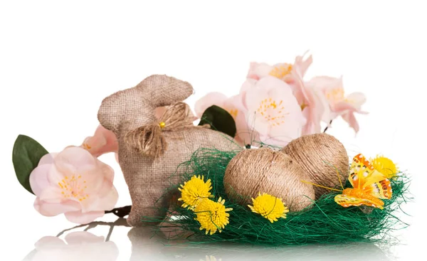 Paaseieren in nest verstrengeld met touw en konijn, bloemen. — Stockfoto