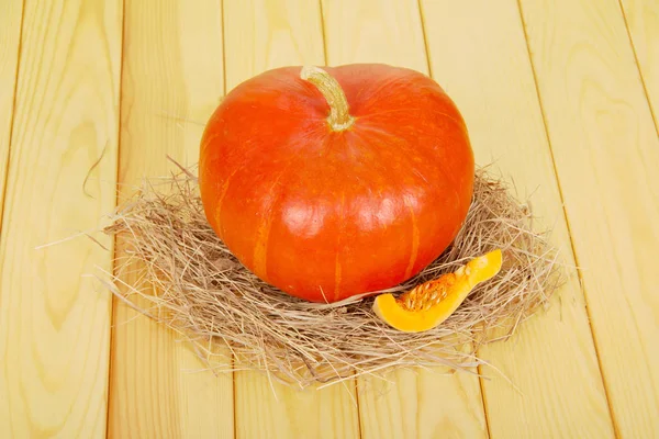 Una calabaza madura entera y rebanada de semillas en hierba seca —  Fotos de Stock