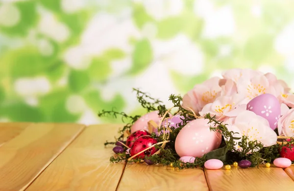 Цветные пасхальные яйца, конфеты, трава, цветы и лента — стоковое фото