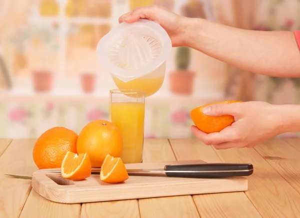 En las manos de las mujeres es parte de naranja y exprimidor, vaso de naranja — Foto de Stock