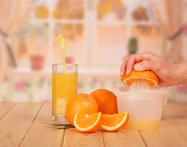 Een glas sinaasappelsap, sinaasappelschijfjes, vrouwenhand. — Stockfoto