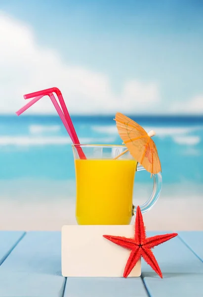 Un verre de jus d'orange avec un parapluie et des pailles — Photo