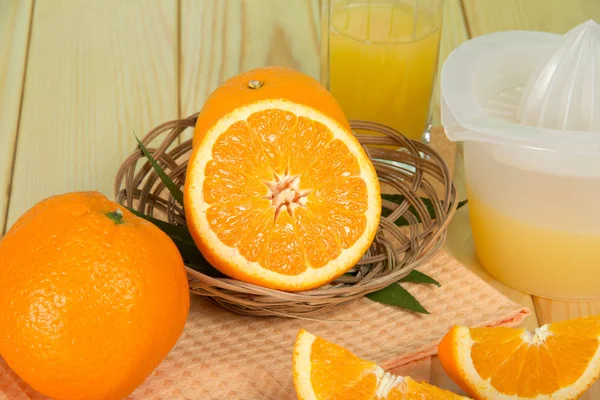 Pomarańcze w koszyku, szklanka soku — Zdjęcie stockowe