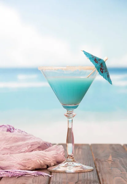 Cocktail with an umbrella and lilac pareo on the background — Stock Photo, Image