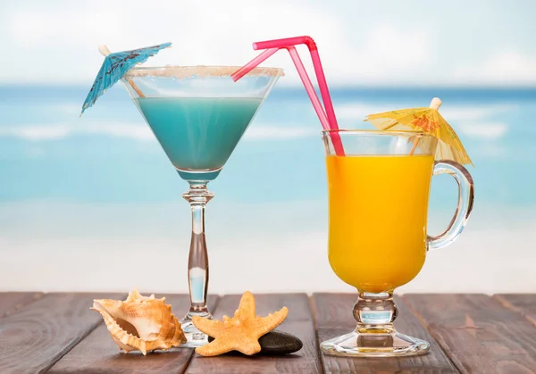 Cocktail e bicchiere di succo d'arancia con ombrelloni, cannucce — Foto Stock