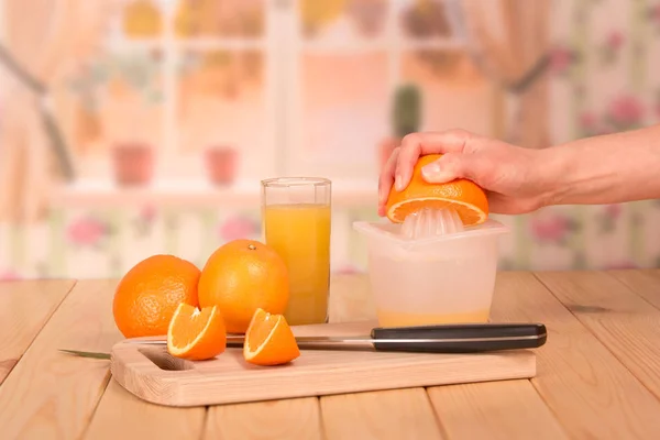 Skleněný pomerančový džus, pomeranče a kousky ženské ruky — Stock fotografie