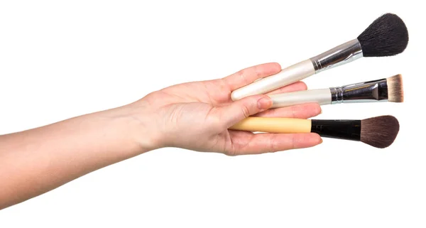 Tre kosmetiska borstar i kvinnlig hand isolerade på vit — Stockfoto