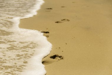Deniz kıyısında çıplak ayak izi var.