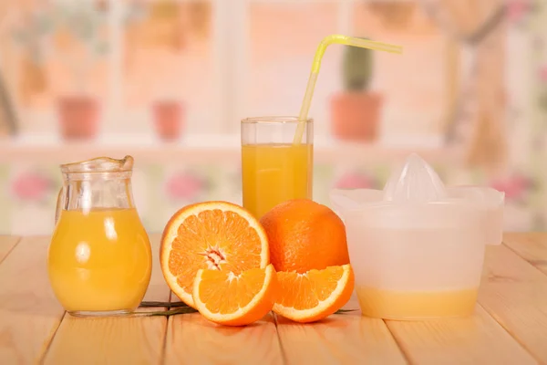Jug and glass of fresh orange juice with straw, orange half — Stock Photo, Image