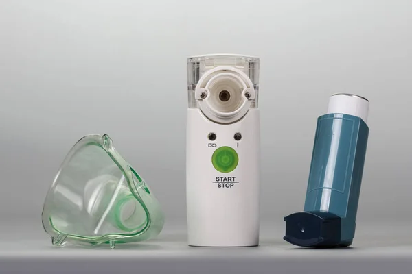 Ultrasonic nebulizer, an inhaler and mask on grey background. — Stock Photo, Image