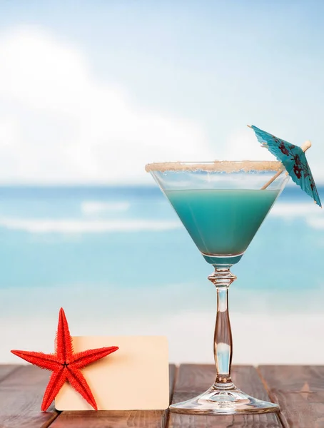 Cocktail met paraplu, blanco kaart en zeester op de achtergrond — Stockfoto