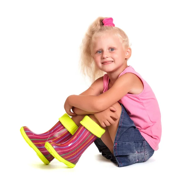 Siedzący słodkie mało blondynka dziewczyna w bluzka, spódnica i gumowe buty — Zdjęcie stockowe