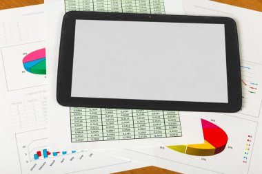 Tablet, sheets of paper account and charts on desktop background