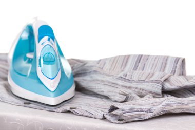 Electric iron and clean laundry, on an ironing board, isolated on white background