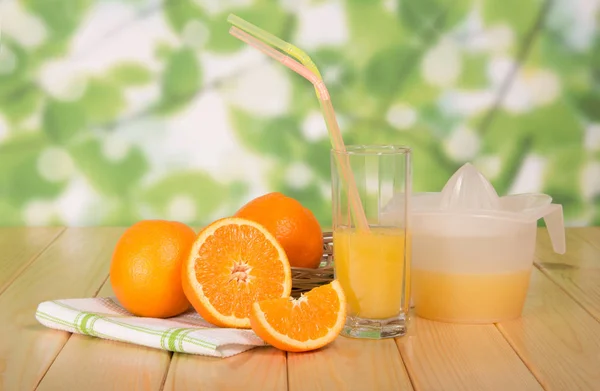 Naranjas, un vaso de jugo, una prensa sobre la mesa — Foto de Stock