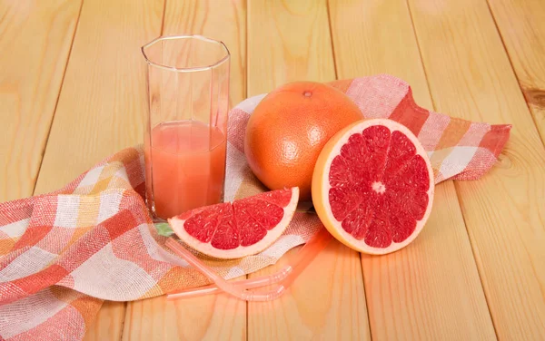 Grapefruit en plakjes, een glas sap op tafel — Stockfoto