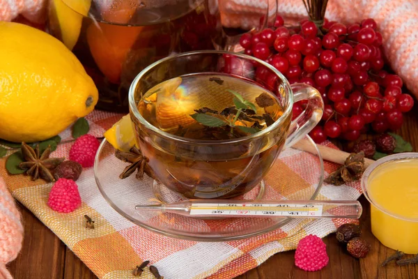 Una taza de té de menta, bayas de un viburnum, un limón y miel — Foto de Stock