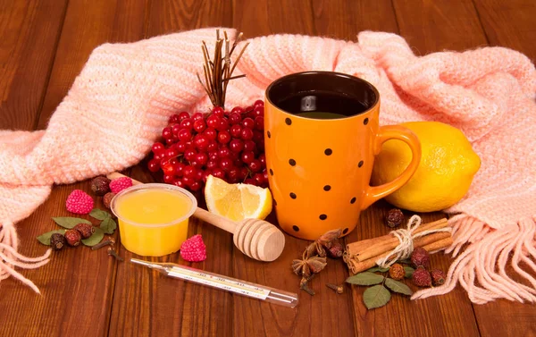 A cup of tea, a viburnum, a lemon and a warm scarf on the table — 图库照片