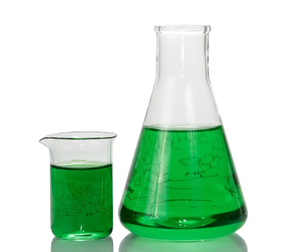 Chemiekolben, Becher mit grünen Flüssigkeiten und Blatt Papier — Stockfoto
