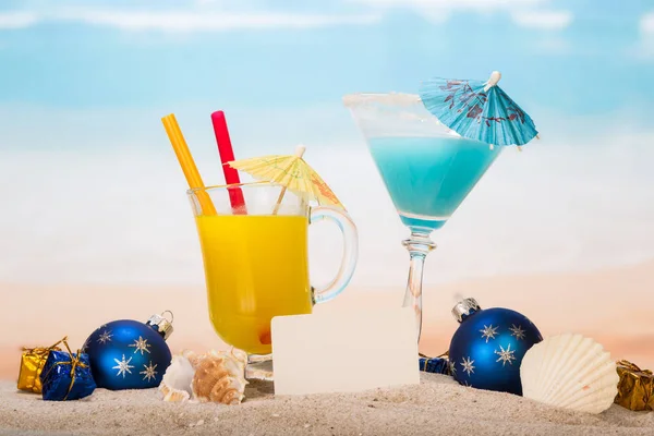 Een cocktail, glas sinaasappelsap, blanco kaart, kerstballen — Stockfoto