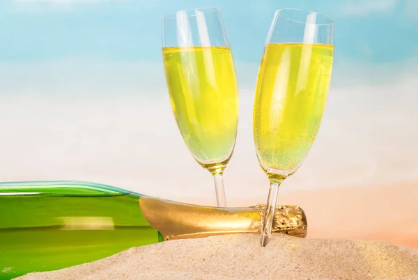 Bottle and two glasses with champagne in the sand — Stockfoto