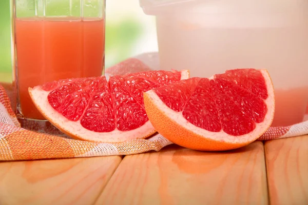 Pieces of grapefruit, juice and napkin on the table — 图库照片