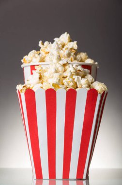 Two striped boxes filled with popcorn on gray background.