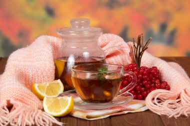 Bunch of viburnum, cup of hot tea with lemon from cold, on wooden table
