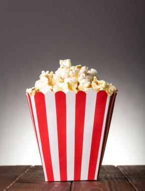 Large striped square box filled with popcorn on gray background.