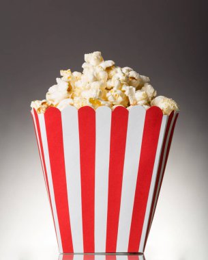 Large striped square box filled with popcorn on gray background.