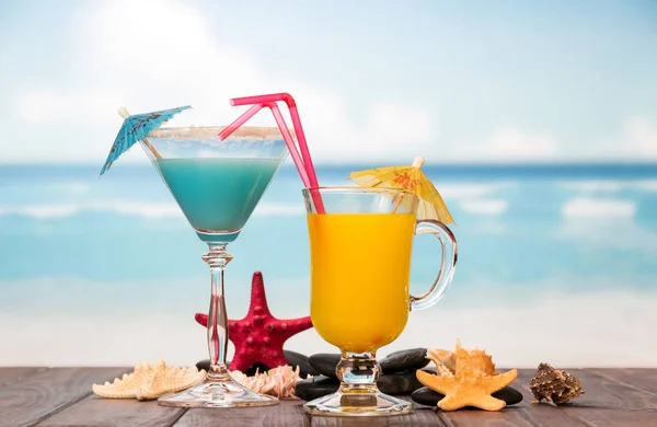 Cóctel y vaso de zumo de naranja con sombrillas, pajitas — Foto de Stock