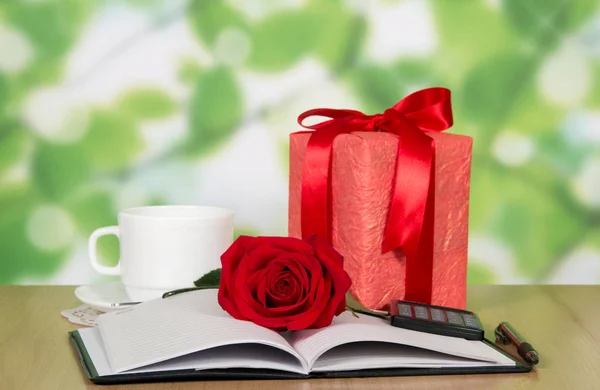Cadeau, rode roos, notitieblok en pen op tafel — Stockfoto