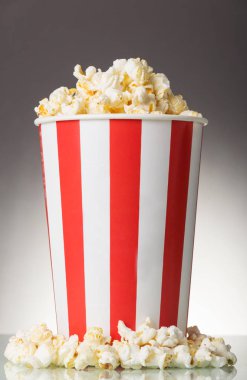 Gri arka planda çizgili patlamış mısır ve patlamış mısır kutusu.