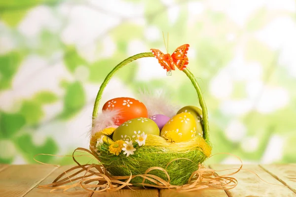 Huevos de Pascua en cesta, mariposa y cinta en verde abstracto . —  Fotos de Stock