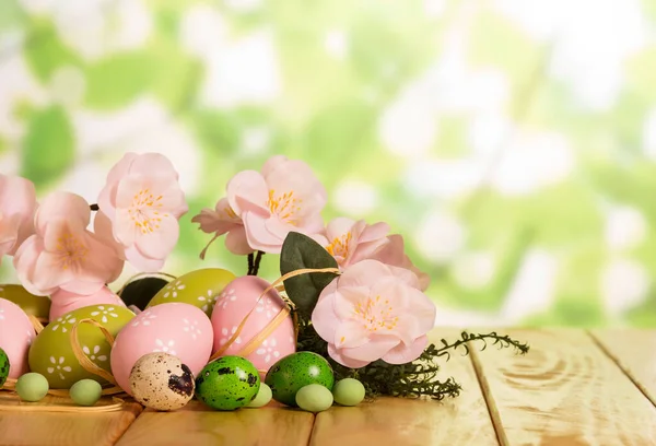 Easter eggs, candy, grass, flowers and ribbon on abstract green. — Stock Photo, Image