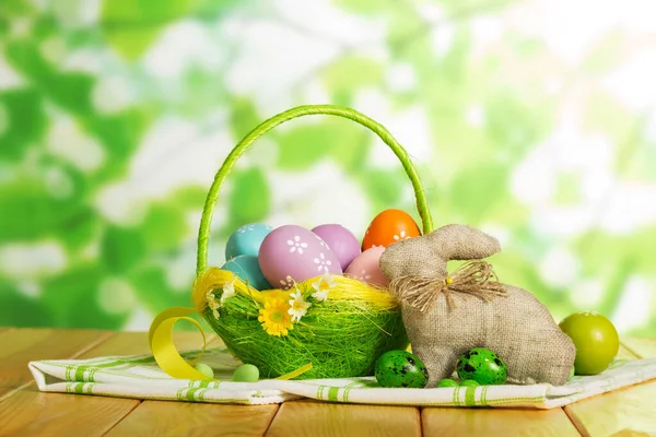 Œufs de Pâques colorés dans le panier et lapin de Pâques, bonbons, ruban — Photo