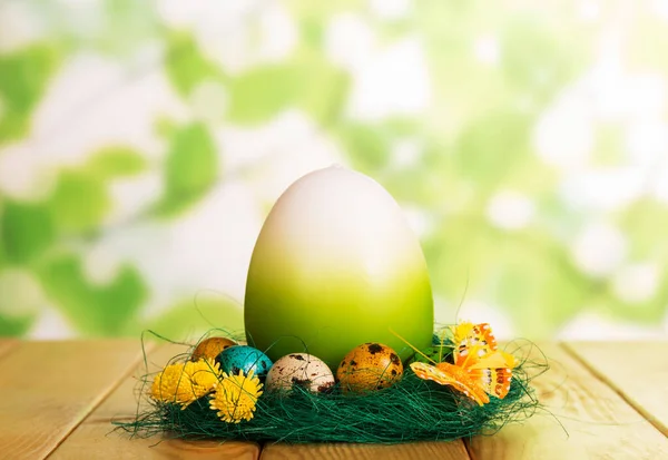 Huevos de Pascua en el nido y uno grande en verde abstracto . —  Fotos de Stock