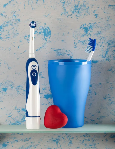 Elektrisk Och Vanlig Tandborste Glas Litet Hjärta Blå Bakgrund — Stockfoto
