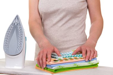 Elektrikli demir ve kadın elleri, beyaz üzerine izole edilmiş temiz çarşafları istifler.