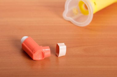 Bebek maskesiyle taşınabilir küçük astım spreyi masanın üzerinde duruyor.