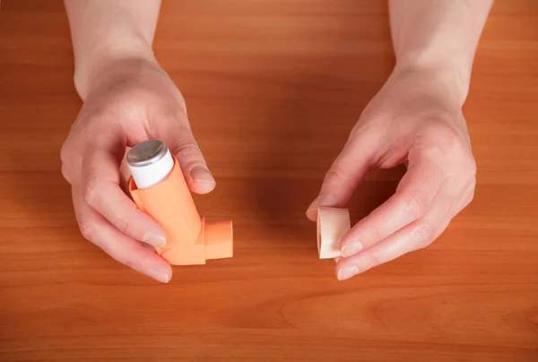 Las manos femeninas sostienen el inhalador portátil en la mesa — Foto de Stock