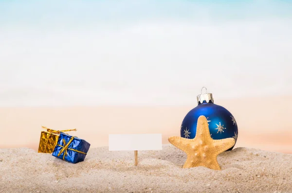 Een blanco kaart op pin, kerstbal en geschenken, zeester in de s — Stockfoto