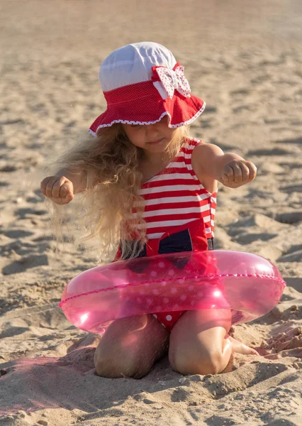 Blond pige i redningskrans ring på sandet - Stock-foto