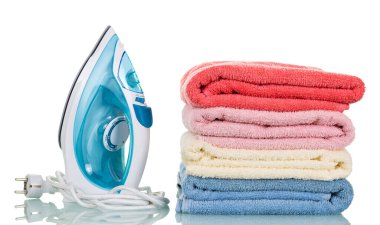 Elektrikli ütü, ütülenmiş havluların yanında, beyaz üzerine izole edilmiş.