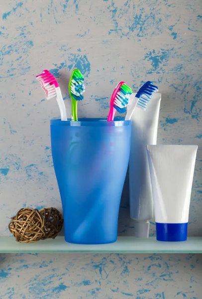 Toothpaste and toothbrushes on shelf — Stock Photo, Image