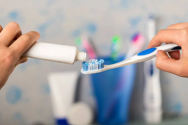 Handen knijpen tandpasta op de borstel in de badkamer — Stockfoto