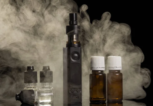Nube de vapor de un cigarrillo electrónico, botellas de líquido para fumar, aislado en negro — Foto de Stock