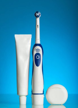 Mavi arka planda ağız temizliği, diş macunu ve iplik için elektrikli fırça