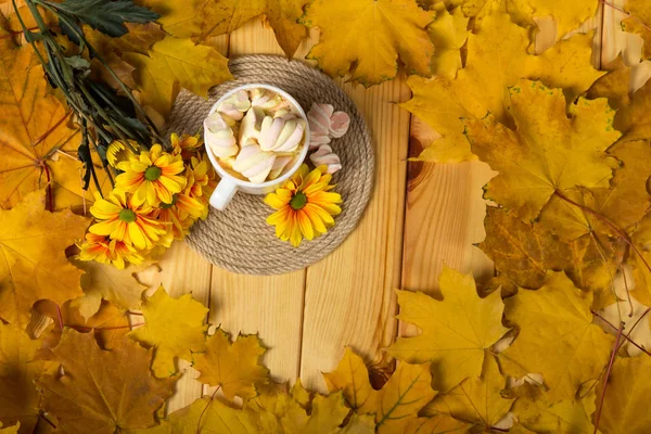 Sonbahar yaprakları ve çiçeklerin arka planında lokumlu sıcak kahve. — Stok fotoğraf