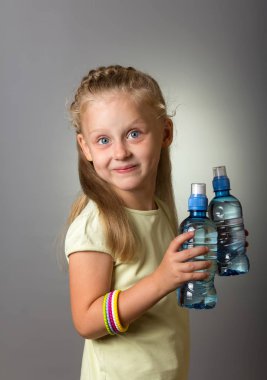 Gri üzerine iki şişe su tutan büyüleyici kız.